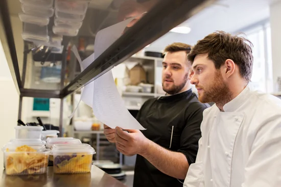 un manager de transition passe les consignes à son cuisinier